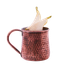 Ein kupferner Becher mit einer strukturierten Oberfläche, gefüllt mit einer klaren Flüssigkeit und dekoriert mit Birnenscheiben.