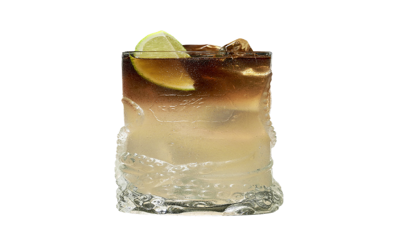 Ein transparentes Glas mit einem erfrischenden Cocktail, das mit Eis gefüllt ist und eine Limettenscheibe oben hat.
