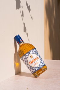 Ein Sonnenstrahl beleuchtet die Flasche CANONITA, die schräg an einer Wand steht und interessante Schatten wirft.