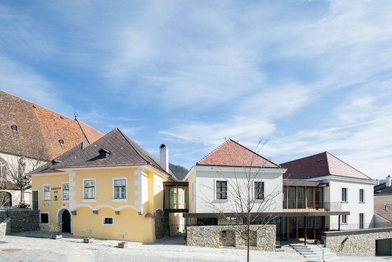 Die Szene zeigt eine gelungene Kombination aus historischen und zeitgenössischen Baustilen, unter einem strahlend blauen Himmel.