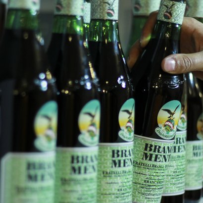 Die Flaschen mit dem charakteristischen Branca Menta Etikett stehen nebeneinander, während eine Hand eine Flasche anfasst.