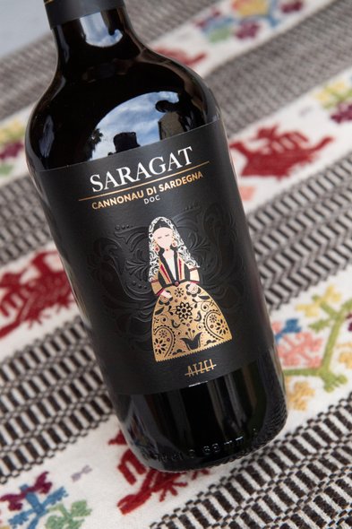 Eine elegante Weinflasche mit dem Etikett 'Saragat', das eine traditionell gekleidete Frau in einem goldenen Kleid zeigt.