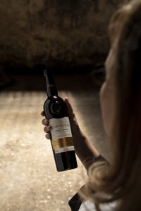 In einem rustikalen Raum wird eine Flasche Sherry von einer Person bewundert, die sich auf die Details des Etiketts konzentriert.