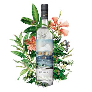 Eine Flasche Humboldt Gin steht im Mittelpunkt, umgeben von üppigen, bunten Pflanzen und Blumen, die eine lebendige Atmosphäre schaffen.