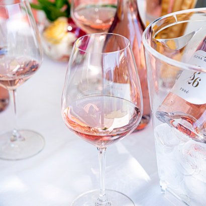 Ein ansprechendes Arrangement aus Roséwein, Gläsern und einer dekorativen Flasche, das eine einladende Atmosphäre schafft.