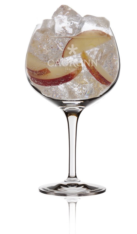 Das Glas ist gefüllt mit sprudelndem Wasser, Eis und frischen Apfelstücken, ideal für einen heißen Tag.