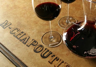 Ein rustikales Setting mit Rotwein in Gläsern und einer Dekantierkanne, umgeben von einer edlen, geprägten Oberfläche.