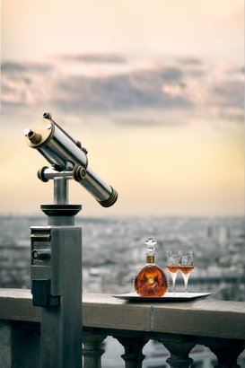Ein Teleskop blickt über die Stadt, während eine Flasche Cognac und Gläser auf einem silbernen Tablett bereitstehen.