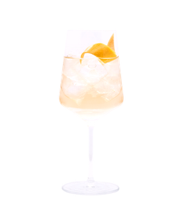 Hellgoldener Drink mit Eiswürfeln und einer geschwungenen Zitronenzeste in einem hohen Stielglas vor weißem Hintergrund.