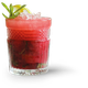 Ein Glas mit einem leuchtend roten Getränk, das mit Eis gefüllt ist und mit einer Limettenscheibe sowie Minzblättern geschmückt ist.