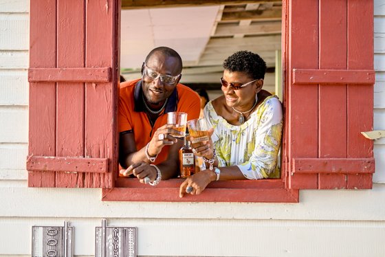 Ein Mann und eine Frau stehen am Fenster, halten Gläser in der Hand und teilen einen herzlichen Moment voller Freude.