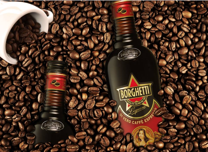 Inmitten von Kaffeebohnen steht eine Borghetti-Flasche, während eine Tasse mit Bohnen im Hintergrund sichtbar ist.