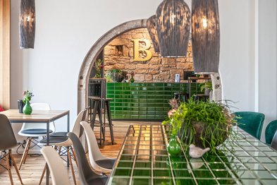 Der Innenraum zeigt eine harmonische Kombination aus Holz, grünen Fliesen und eleganten Lampen, die eine gemütliche Stimmung erzeugen.