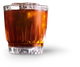 Ein Glas mit einem aromatischen, dunklen Getränk und Eiswürfeln, das eine einladende Atmosphäre ausstrahlt.