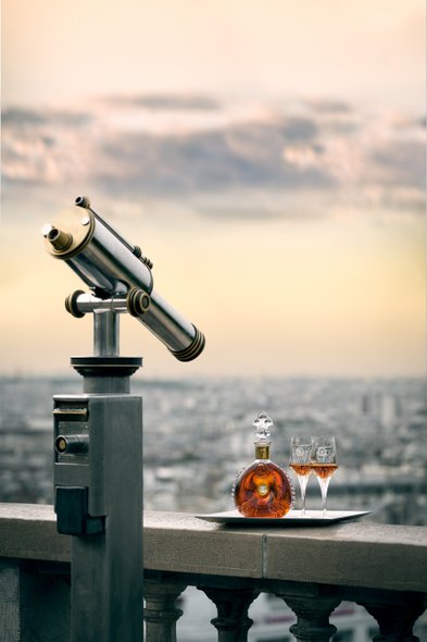 Ein Teleskop blickt über die Stadt, während eine Flasche Cognac und Gläser auf einem silbernen Tablett bereitstehen.