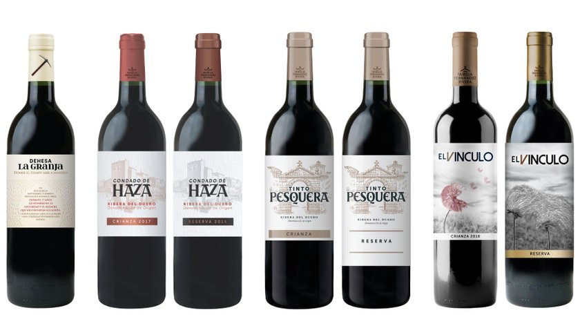 Sieben Flaschen Rotwein stehen nebeneinander, jede mit einem einzigartigen Etikett und unterschiedlichen Jahrgängen.