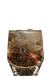 Ein transparentes Glas, gefüllt mit einem goldenen Getränk und Eis, das auf einem dunklen Hintergrund steht.