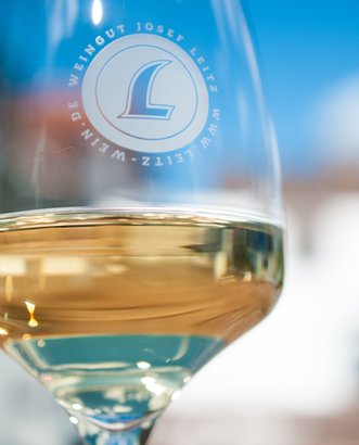 Das Glas zeigt einen goldenen Wein, während das Logo des Weinguts Josef Leitz klar erkennbar ist.