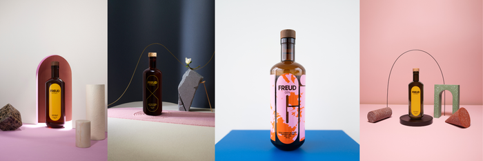 Eine stilvolle Anordnung von Flaschen mit Whisky und Gin, umgeben von geometrischen Formen und sanften Farben auf einem Tisch.