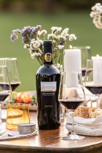 Eine elegante Flasche Fantini Wein steht im Mittelpunkt eines festlich gedeckten Tisches mit Gläsern und Kerzen.