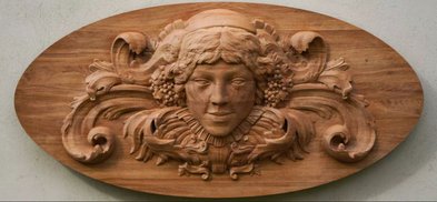 Eine kunstvoll geschnitzte Holzplatte zeigt ein Gesicht mit sanften Zügen und floralen Verzierungen, die Eleganz ausstrahlen.
