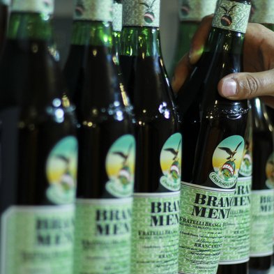 Die Flaschen mit dem charakteristischen Branca Menta Etikett stehen nebeneinander, während eine Hand eine Flasche anfasst.