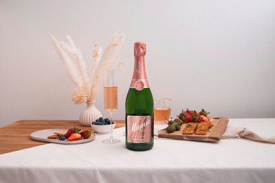 Eine Flasche Mumm Rosé-Sekt steht auf einem Tisch, umgeben von frischen Erdbeeren, Blaubeeren und knusprigen Snacks.