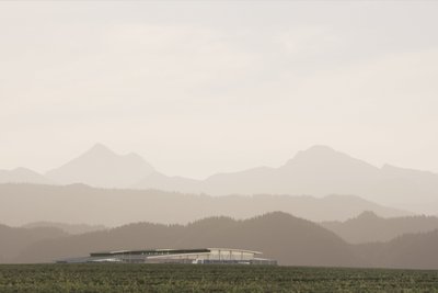 Die sanften Konturen der Berge bilden eine malerische Kulisse für ein innovatives Bauwerk in einer ruhigen, ländlichen Umgebung.
