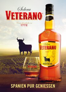 Eine Flasche Solera Veterano mit einem Glas, umgeben von einer malerischen Landschaft und einem ikonischen Stier im Hintergrund.