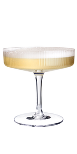 Ein elegantes Glas mit einem schaumigen Getränk, das in sanften Gelbtönen schimmert, steht auf einem weißen Hintergrund.