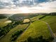Eine malerische Landschaft mit sanften Hügeln, Weinbergen und einem kleinen Dorf, das im warmen Licht der Abendsonne liegt.