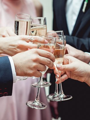 Hände mit Gläsern voller Sekt treffen sich in der Mitte, während die Feiernden einen besonderen Anlass voller Glück und Freundschaft feiern.