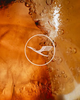 Ein Getränk mit intensiven Farben und Blasen, das in einem Glas mit einem stilisierten Logo präsentiert wird.