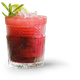 Ein Glas mit einem leuchtend roten Getränk, das mit Eis gefüllt ist und mit einer Limettenscheibe sowie Minzblättern geschmückt ist.